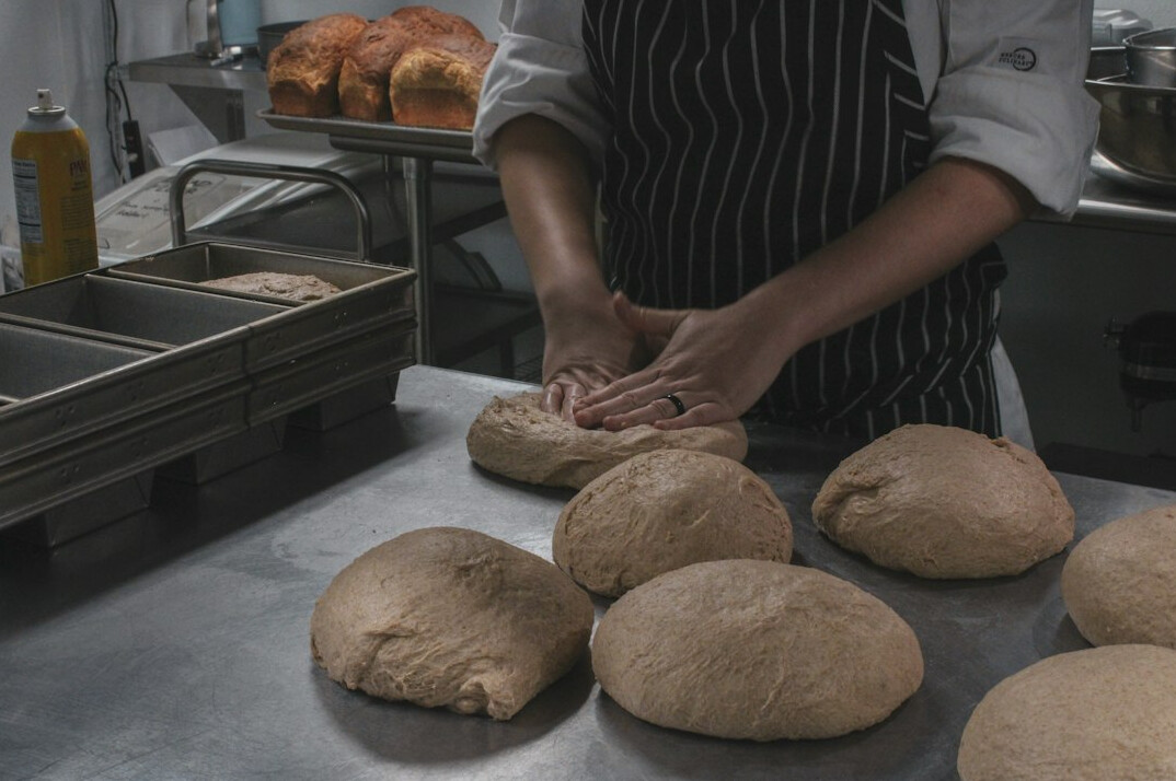Portrait of a young Danish woman baker kneading dough in a small bakery
