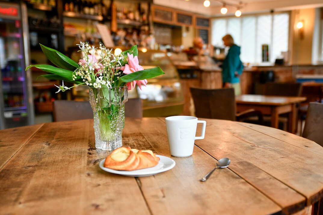 Close view of hands holding a newspaper and coffee cup at a Danish breakfast table